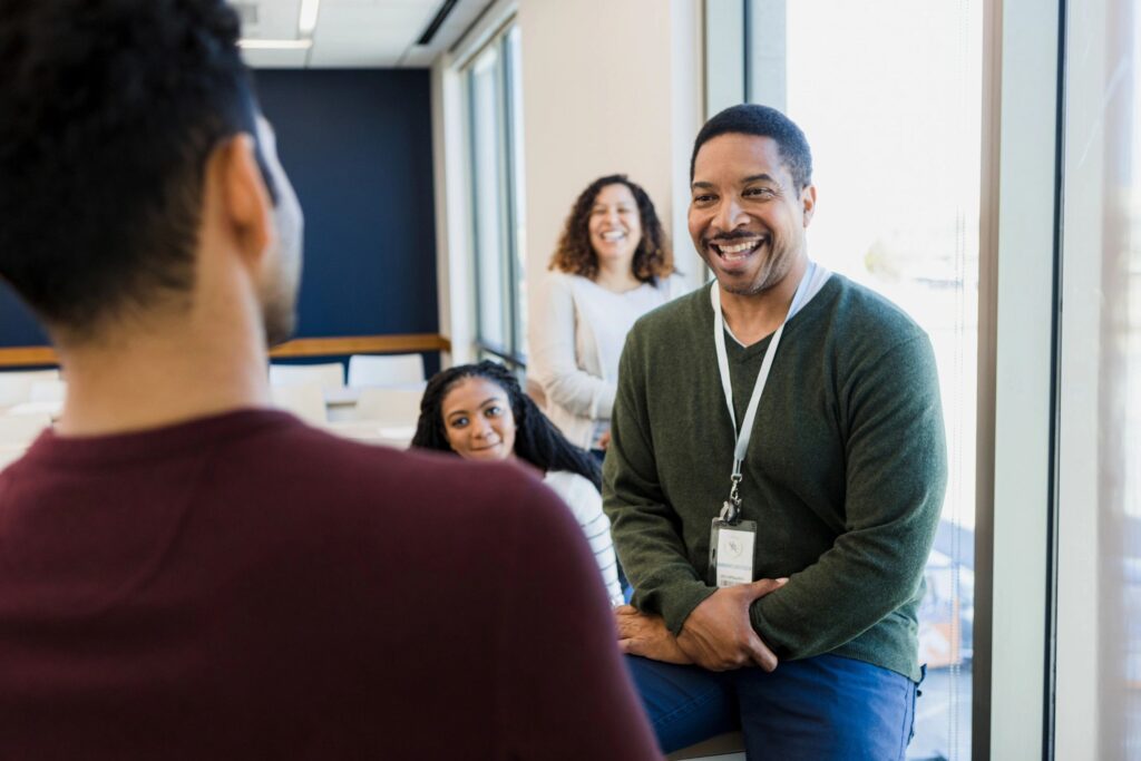 Mature professor smiles and jokes with unrecognizable male student