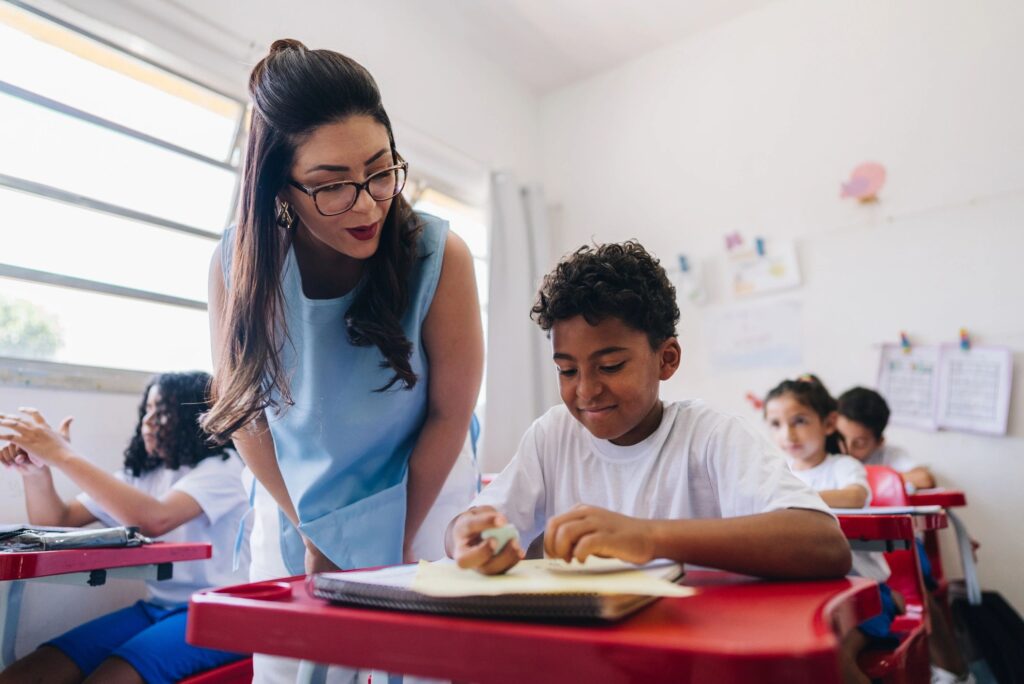 Teacher teaching her student on classroom at school